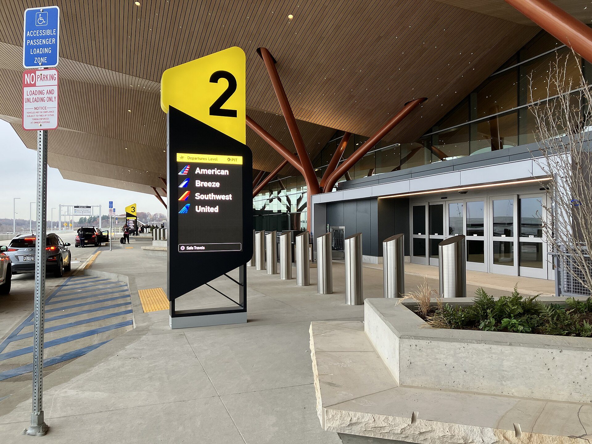 Vehicles unloading passengers at an airport departures drop-off zone