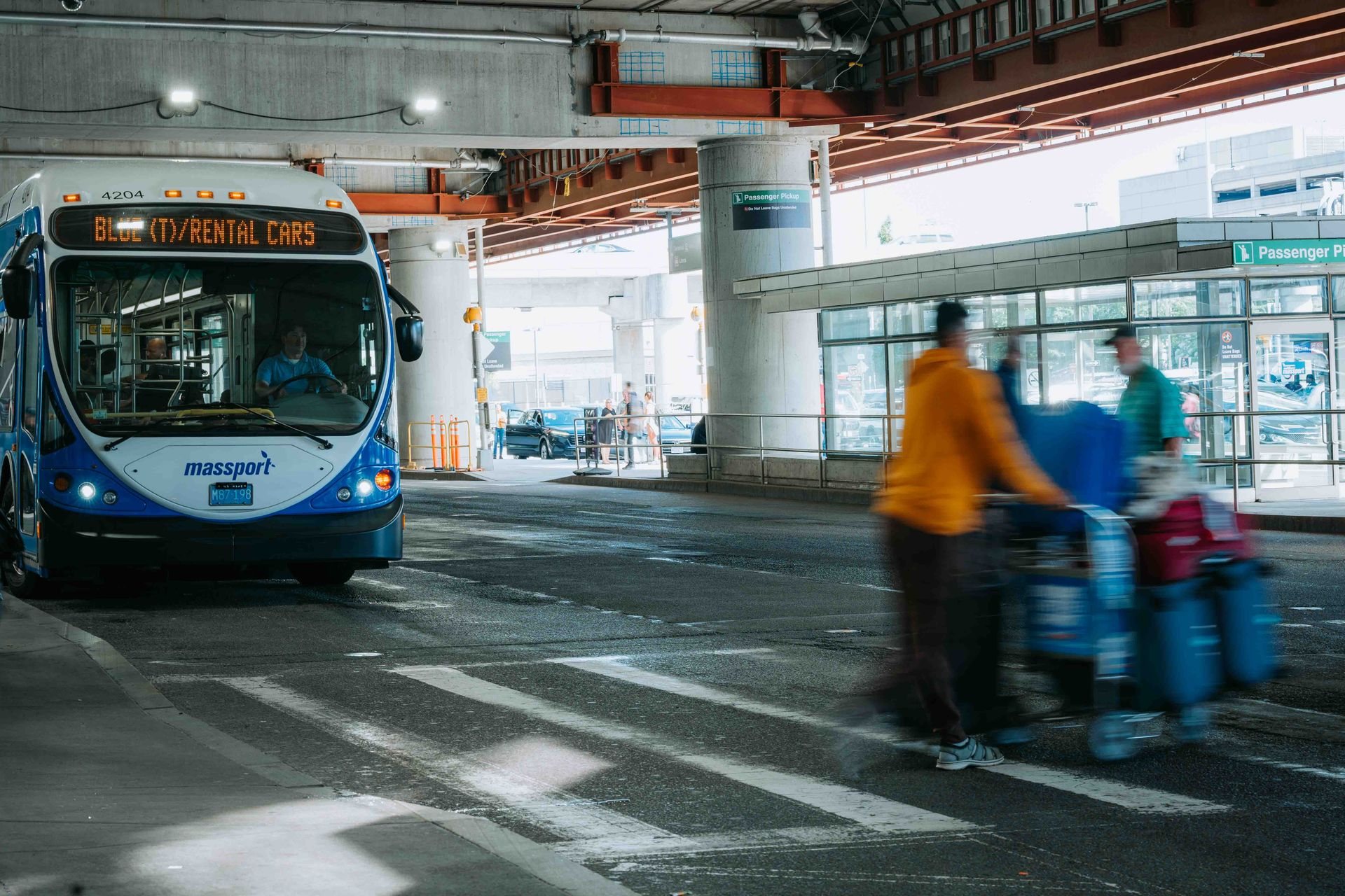Shuttle bus and passengers with luggage at an airport pickup area